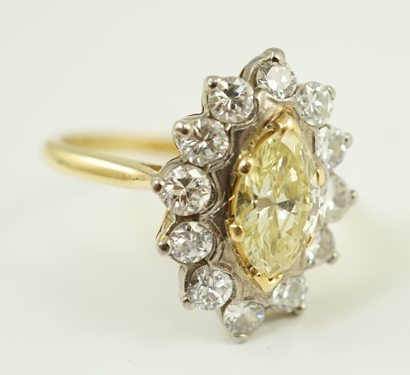 An 18ct gold and single stone fancy yellow diamond set marquise shaped cluster ring with round brilliant cut diamond set border